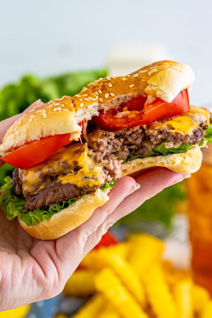 hand holding a smash burger with a bite taken out