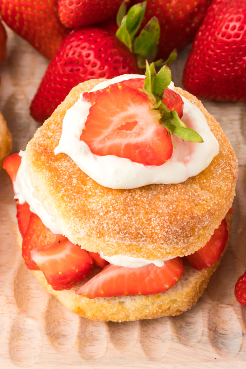 close up of a biscuit strawberry shortcake topped with a dollop of whipped cream and strawberry half