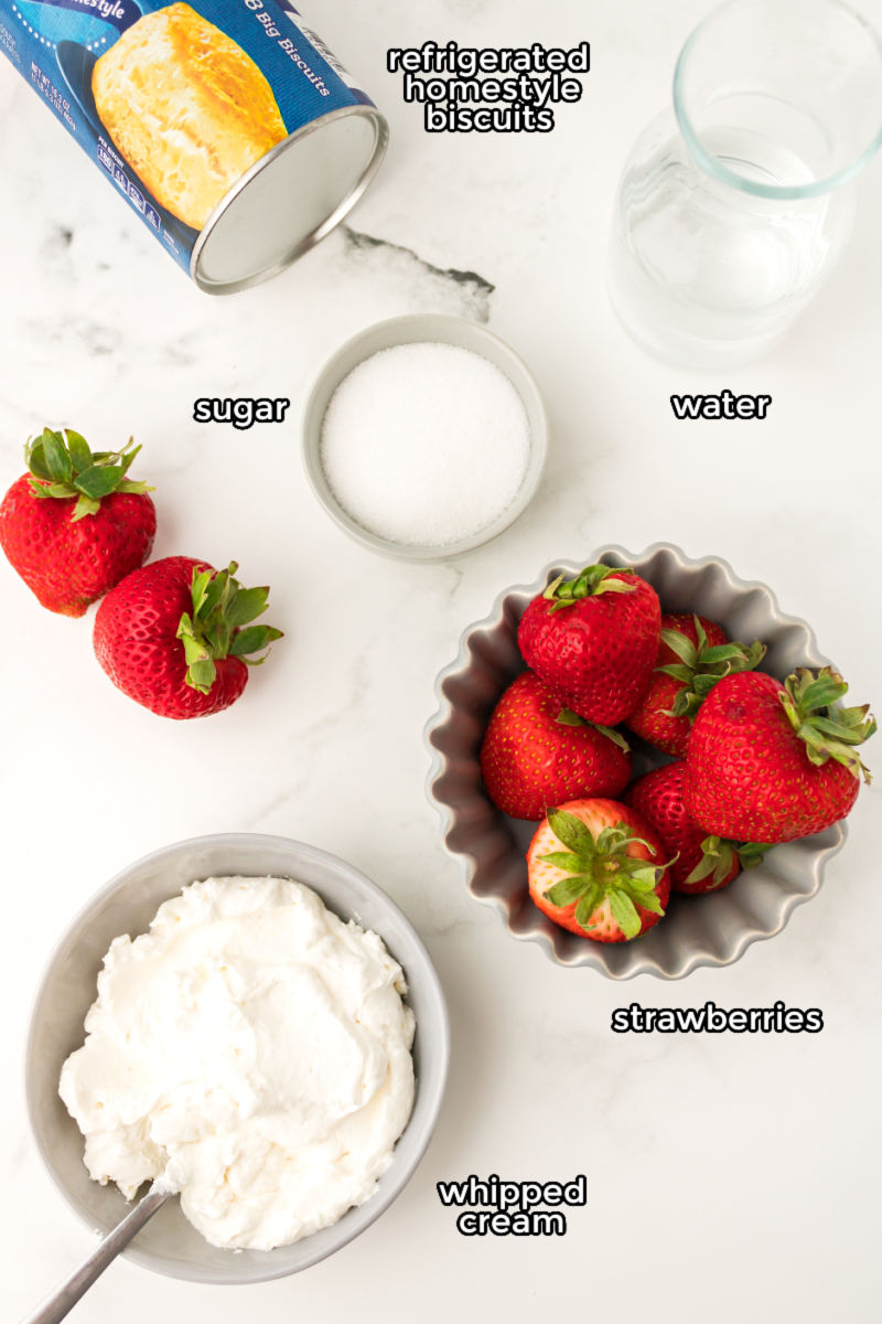 ingredients to make biscuit strawberry shortcake on a counter with text labels