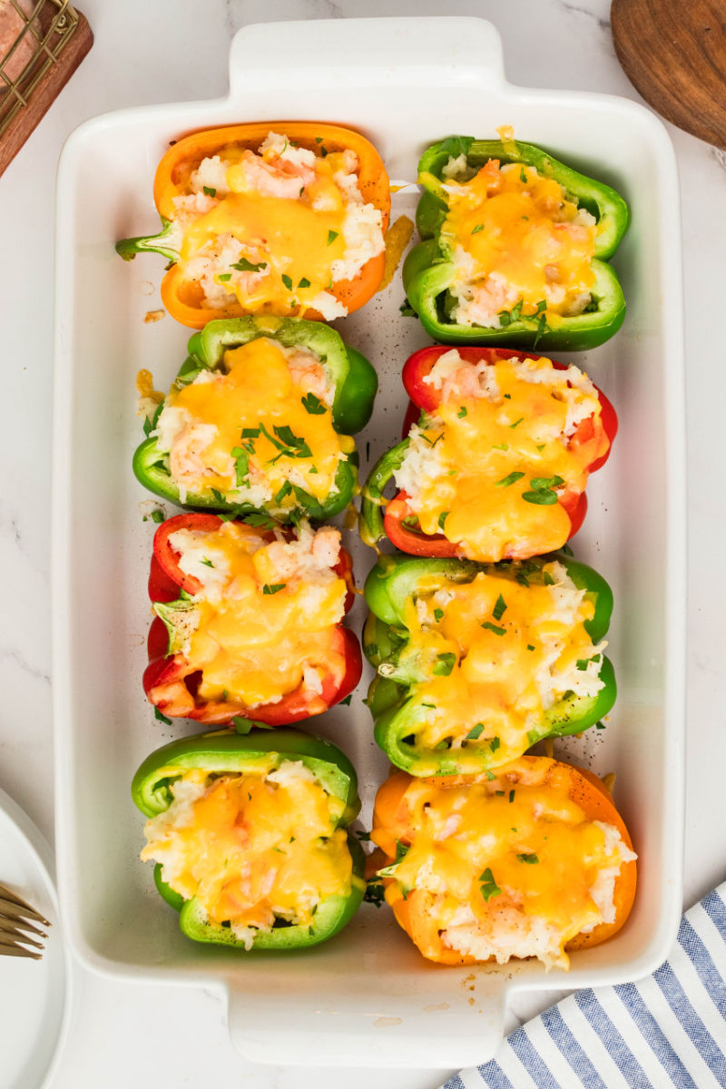 baked shrimp stuffed peppers topped with chopped parsley in a baking dish