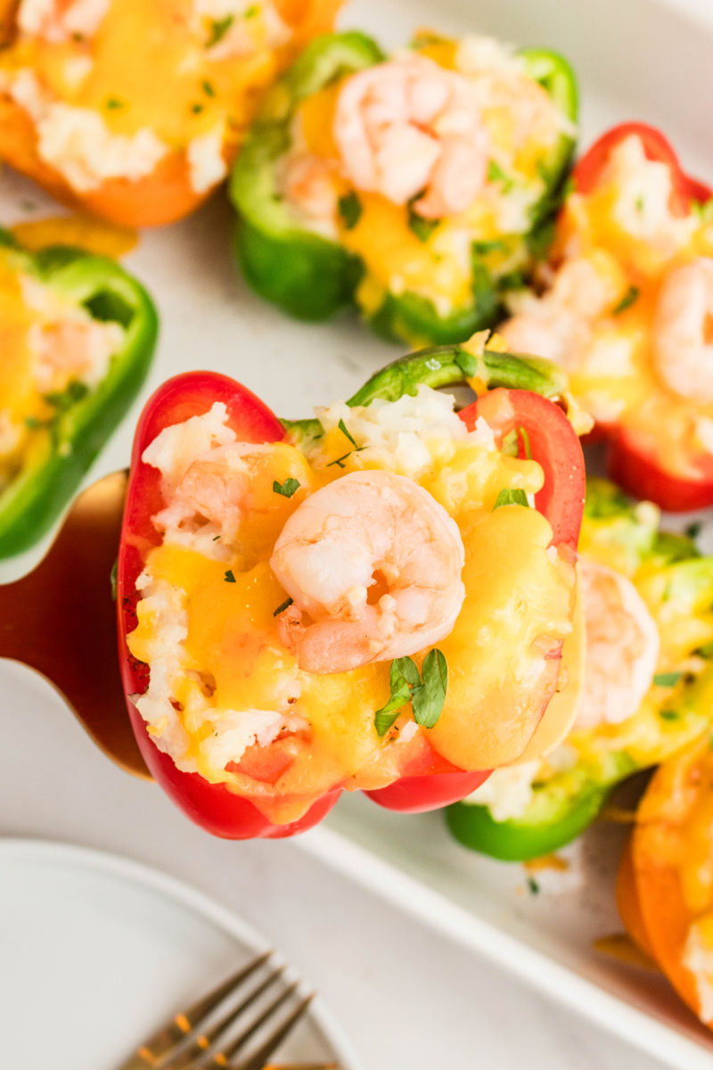shrimp stuffed pepper on a spatula over the baking dish