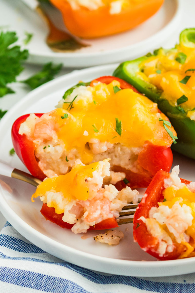 bite of shrimp stuffed pepper on a fork resting on the dinner plate