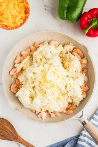 cauliflower rice and mozzarella added to chopped cooked shrimp in a skillet