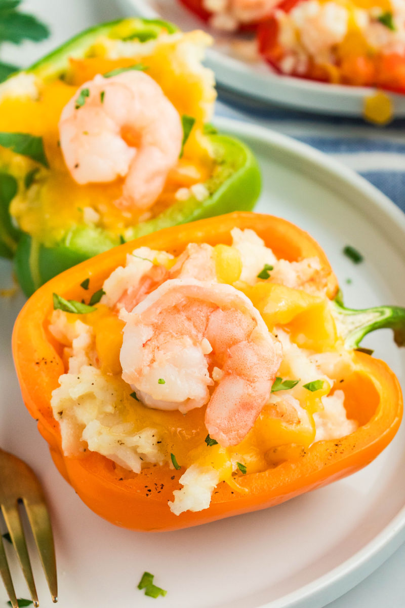 two shrimp stuffed peppers topped with pieces of shrimp on a plate with a fork