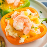square image of shrimp stuffed peppers on a dinner plate with a fork