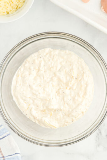 caesar salad dressing, sour crema, and parmesan cheese mixed together in a glass bowl