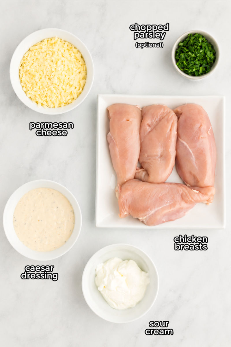 ingredients to make baked caesar chicken laid out on a counter with text labels
