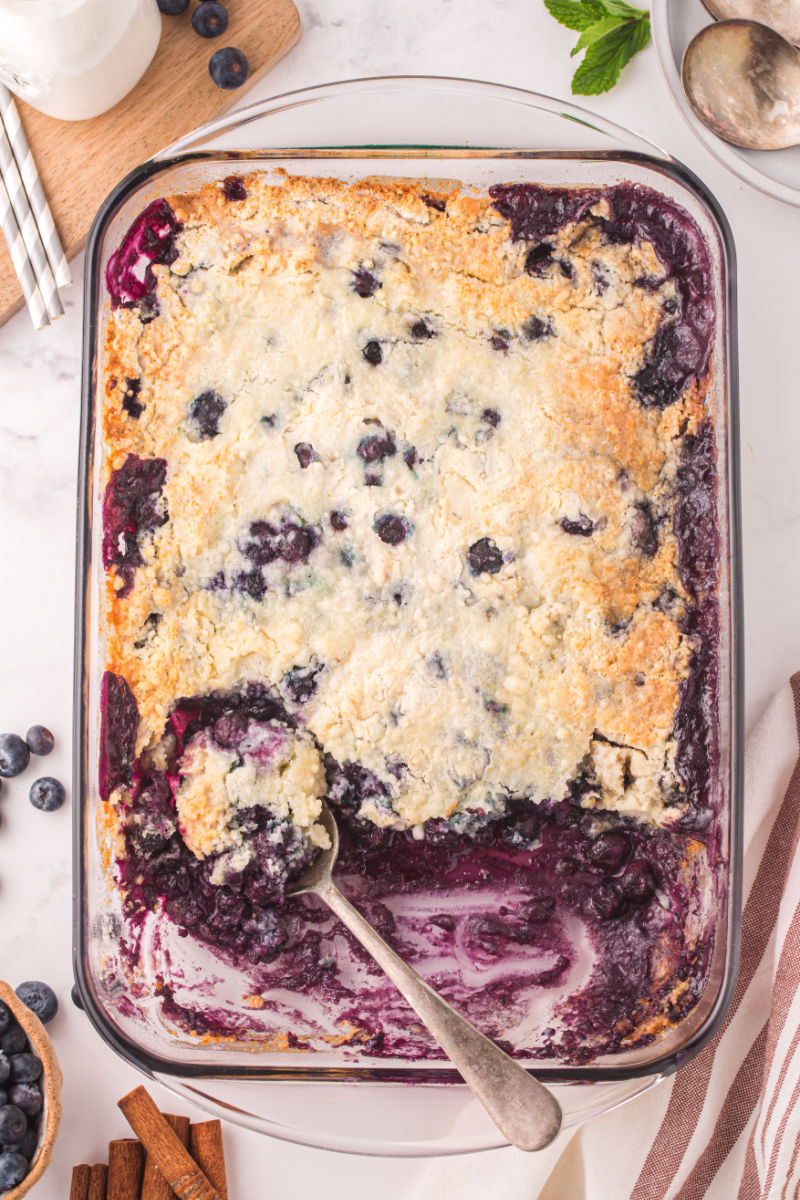 dish of blueberry cobbler with a spoon resting on one side where some of the cobbler has been portioned out