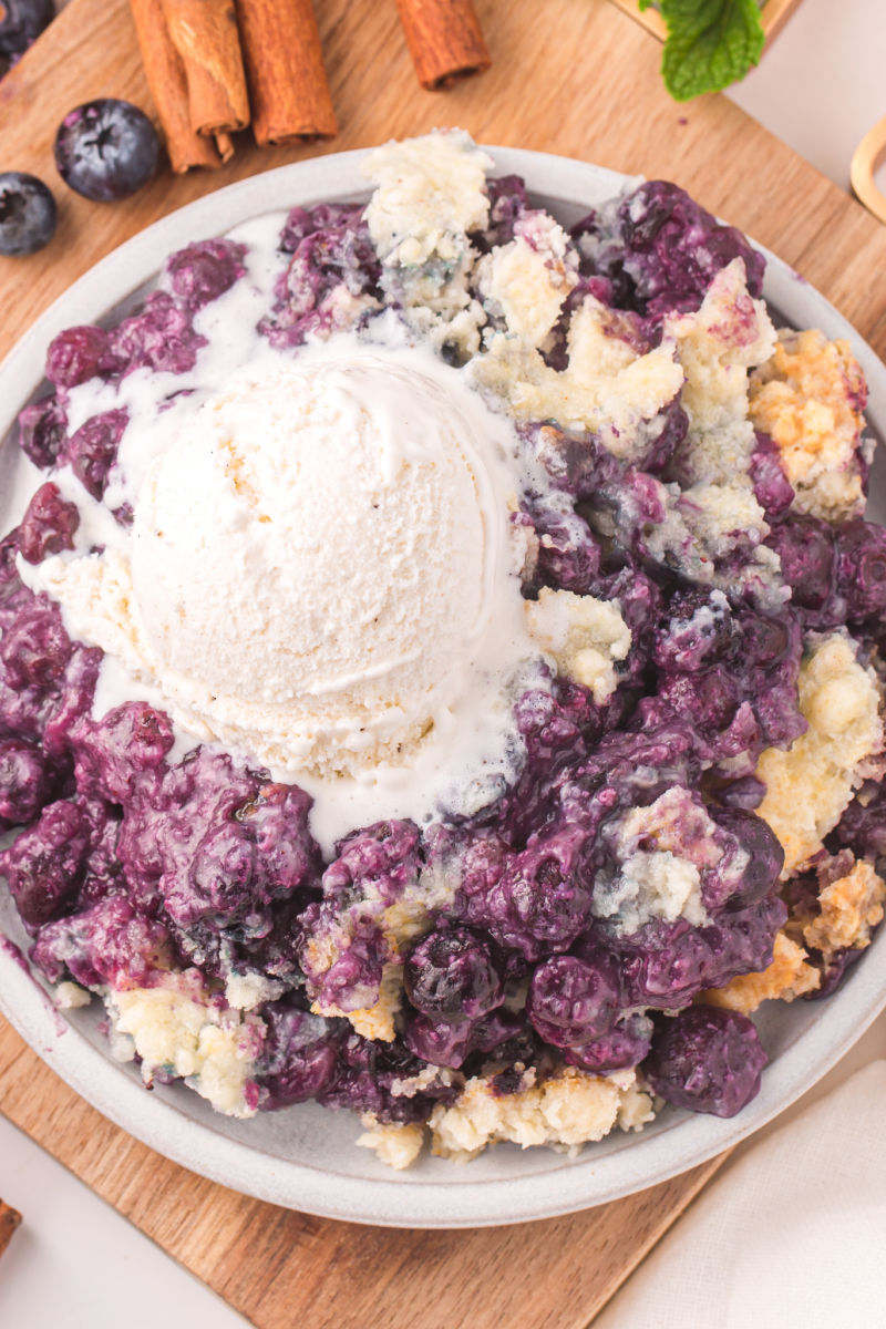 close up looking down at a portion of blueberry cobbler topped with vanilla ice cream
