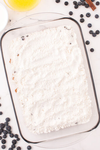 white cake mix spread over frozen blueberries in a baking dish