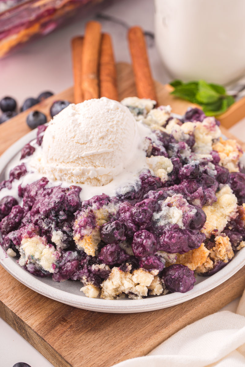 angled view of a portion of blueberry cobbler topped with a scoop on vanilla ice cream
