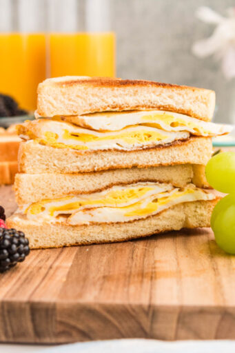 fried egg sandwich halves stacked on each other on a cutting board