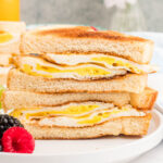 square image of a fried egg sandwich cut in half and stacked on a plate