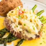 square image of oscar style steak on a plate with a baked potato