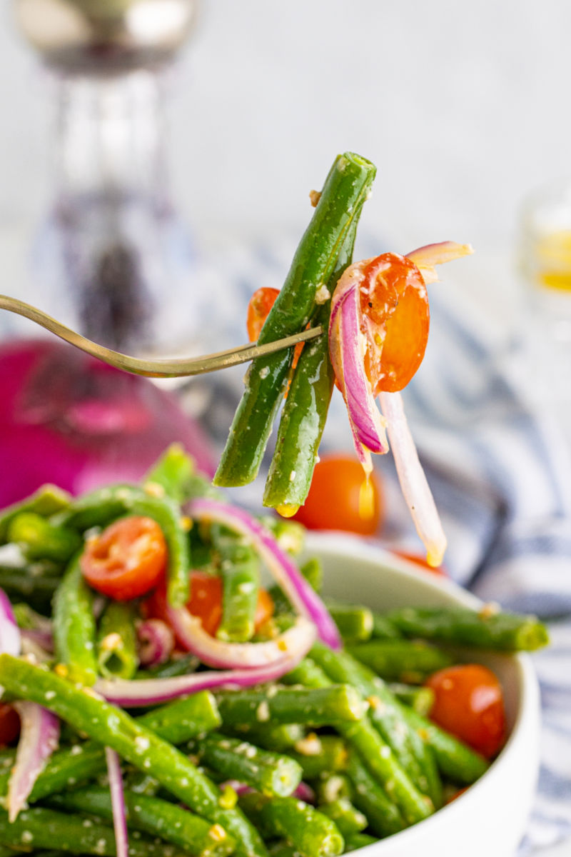 bite of cold green bean salad on a fork over the bowl