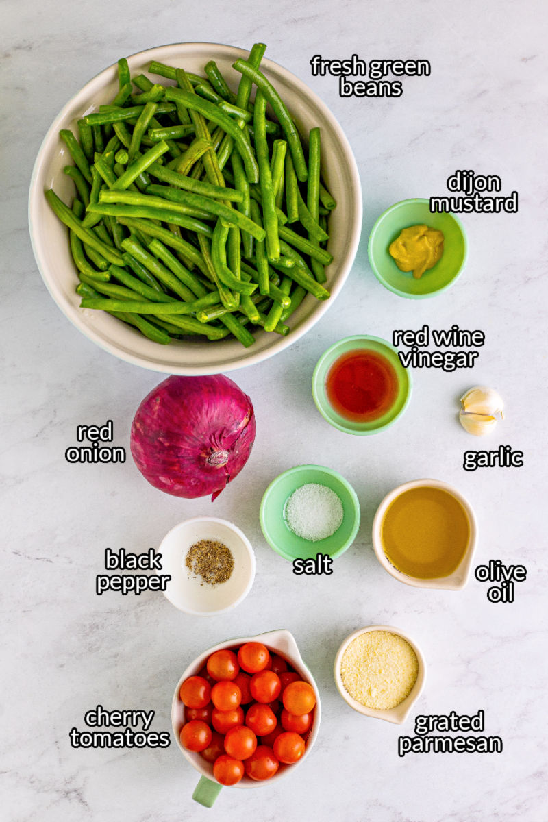 ingredients to make green bean salad laid out on a counter with text labels