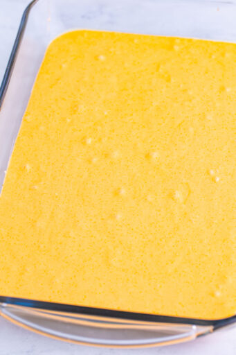 orange poke cake batter in a greased 9x13 baking dish