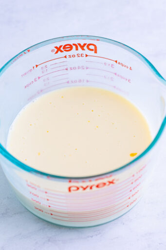 sweetened condensed milk and mandarin orange juice mixed together in a glass Pyrex cup