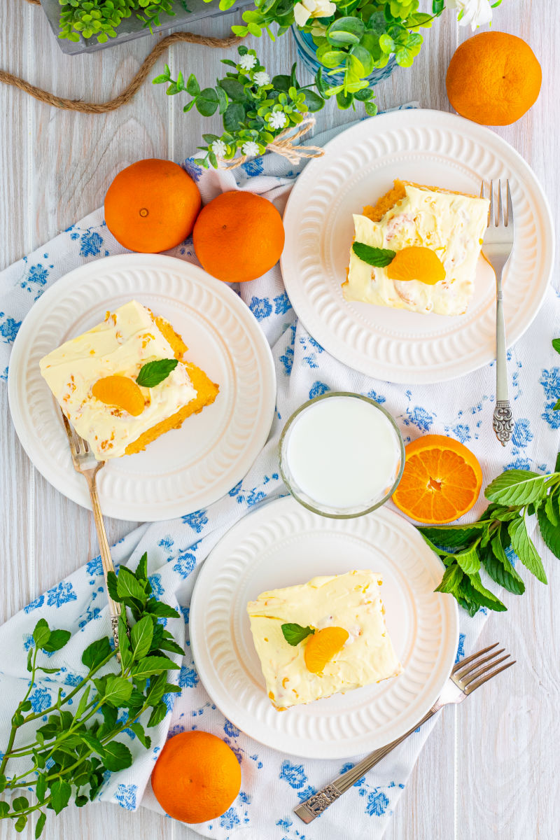 looking down at 3 slices of orange creamsicle cake on plates with forks