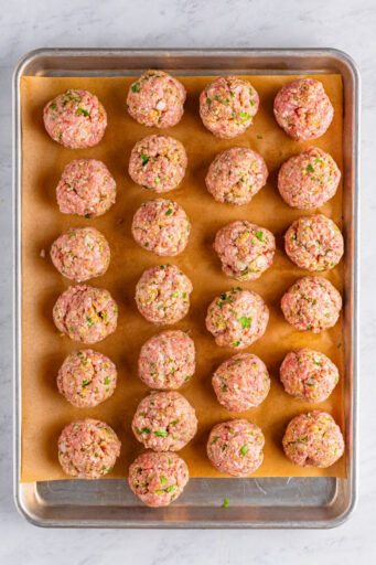 rolled meatballs on a baking sheet