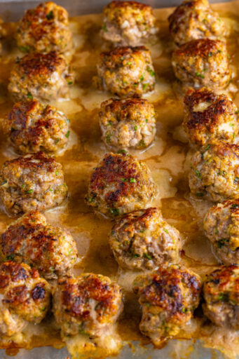 baked italian meatballs on a parchment paper lined baking sheet