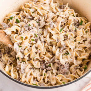 square image of my mom's ground beef stroganoff with cream of mushroom in a pot with a wooden spoon