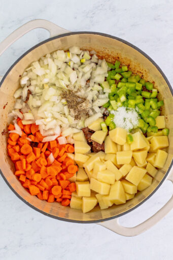onion, celery, carrots, potato, and seasonings added to cooked ground beef in a pot