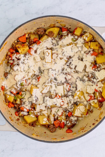 flour sprinkled over sautéed veggies and ground beef in a pot
