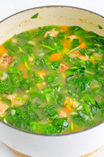 wilted chopped spinach in a pot of italian wedding soup