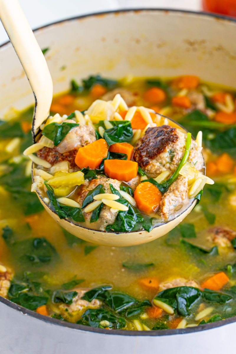 close up of a ladle of italian wedding soup over the pot