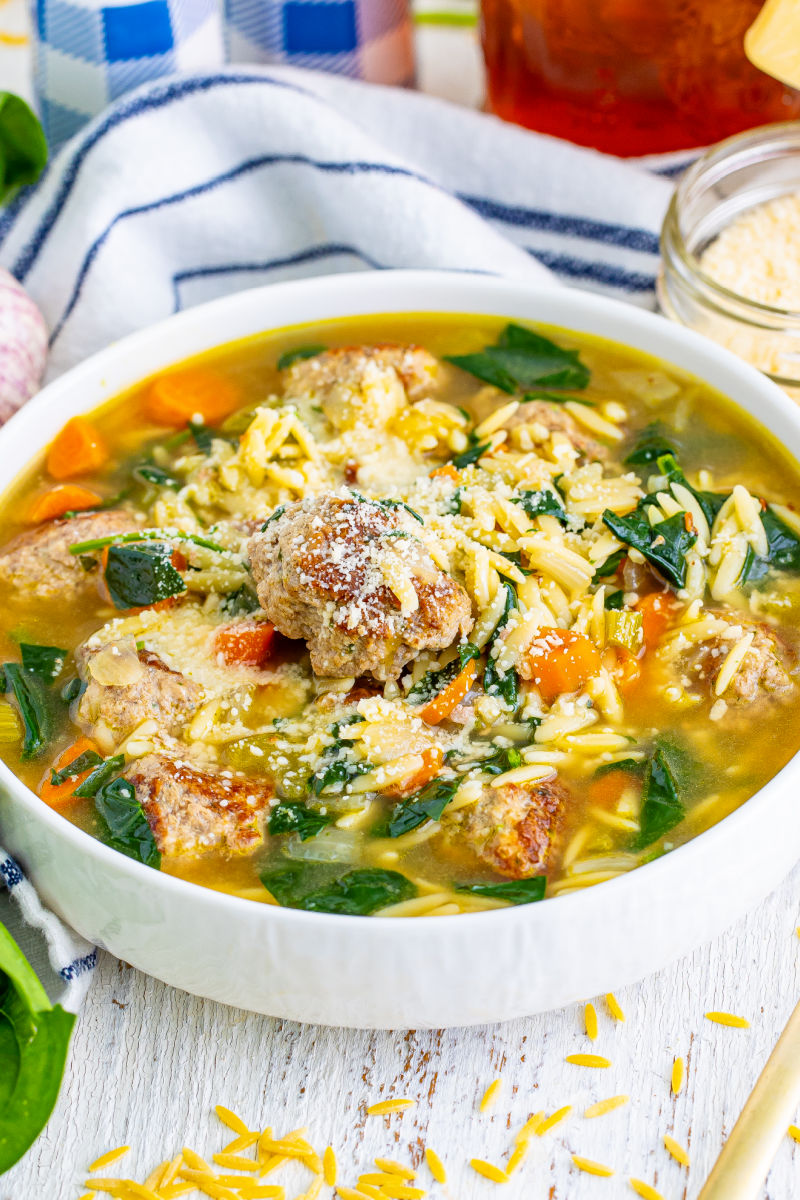 angled view of a bowl of italian wedding soup with grated parmesan sprinkled on top