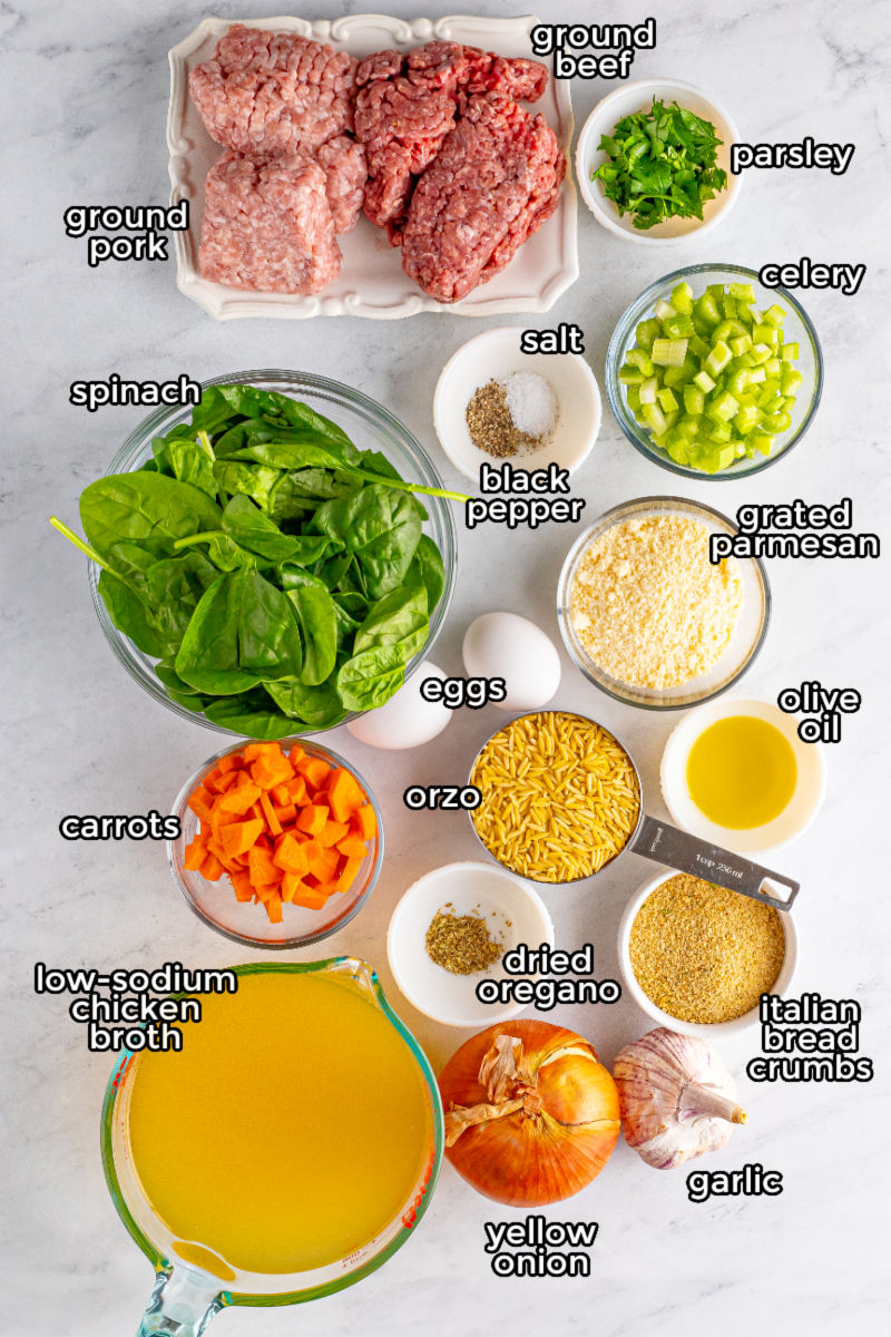 ingredients to make italian wedding soup with homemade meatballs on a counter with text labels