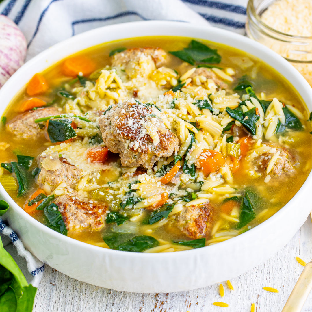 square image of a portion of italian wedding soup in bow with grated parmesan sprinkled on top