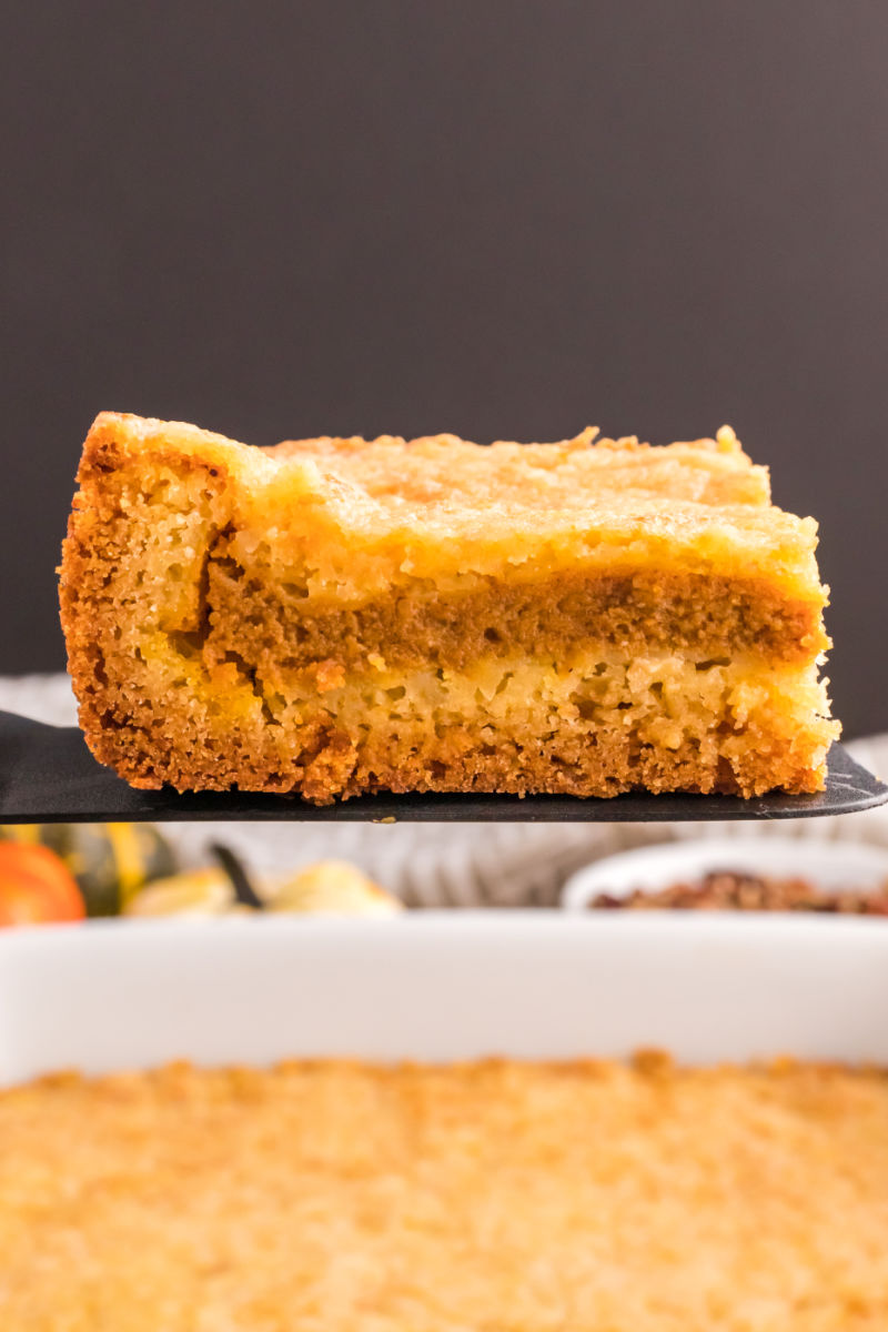 slice of pumpkin pie cake on a spatula over the baking dish