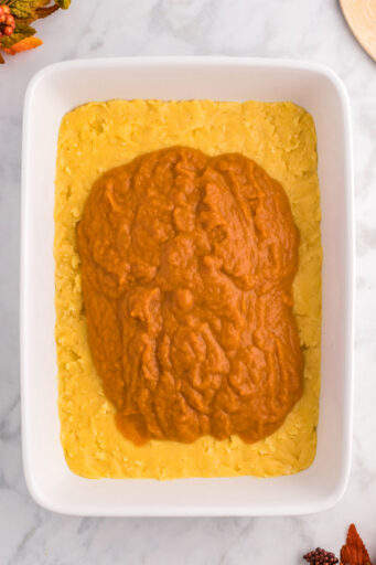 pumpkin filling poured over cake mix crust in a baking dish