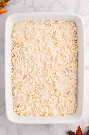 cake mix crumb topping sprinkled over pumpkin filling in a baking dish