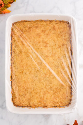 baked and cooled pumpkin pie cake covered in plastic wrap before chilling