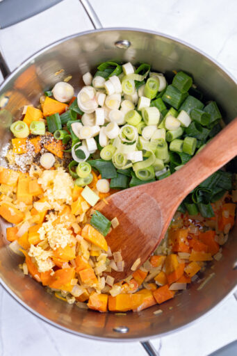 green onion, garlic, seasoning, and ginger add to a pot with carrots and onions