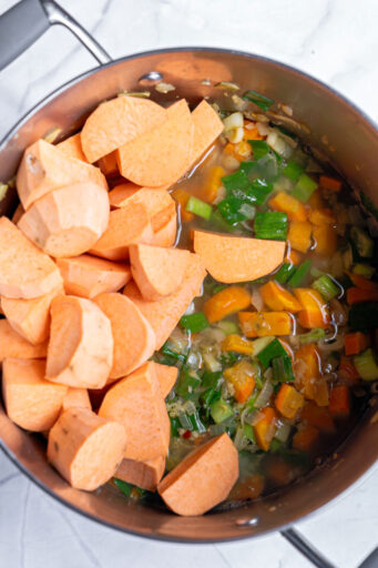 chopped sweet potatoes and water add to a large pot of sautéed vegetables