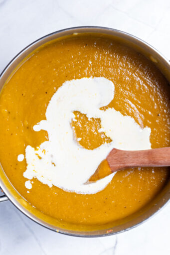 heavy cream added to pureed sweet potato soup in a large pot